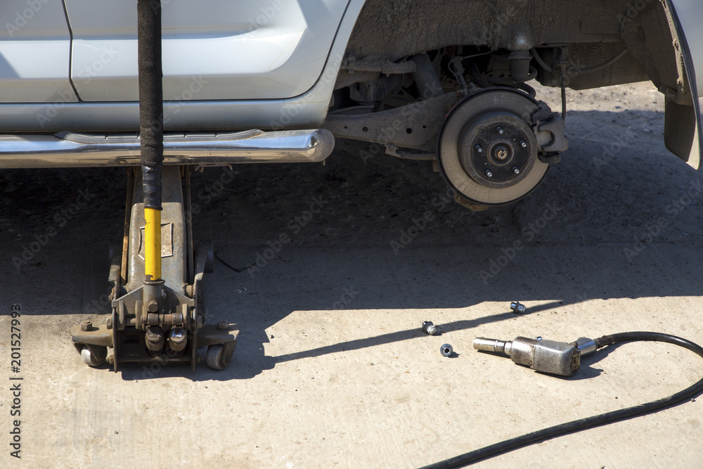 Air impact wrench on the ground, close-up image, near the car with the wheel removed Air impact wrench on the ground, close-up image, near the car with the wheel removed
