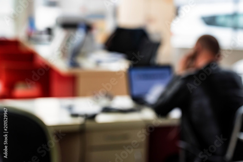 Blurred office interior with man speaking on phone