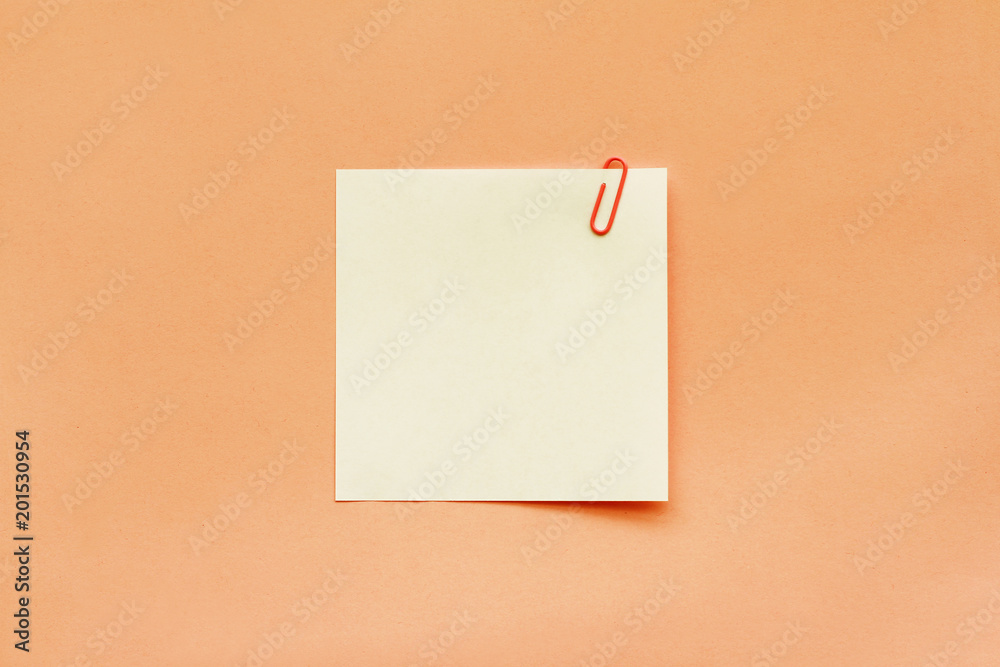 White note paper label with clip on orange background White note paper label with clip on orange background