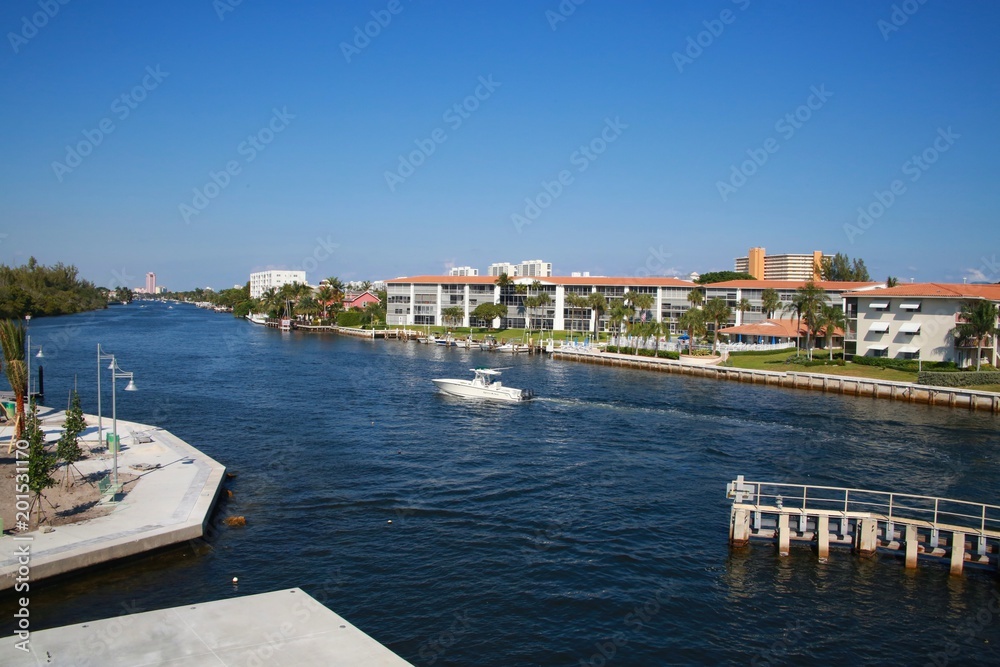 Fototapeta premium Boat Approaches the Intracoastal Waterway Bridge Just North of Hillsboro Blvd. in a Bright Sunny Afternoon with the Boca Hotel and Resort in the Background