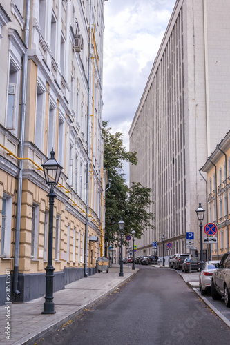 Узкий Староваганьковский переулок в центре Москвы, Россия. Высокие здания разных архитектурных стилей почти полностью закрывают небо photo