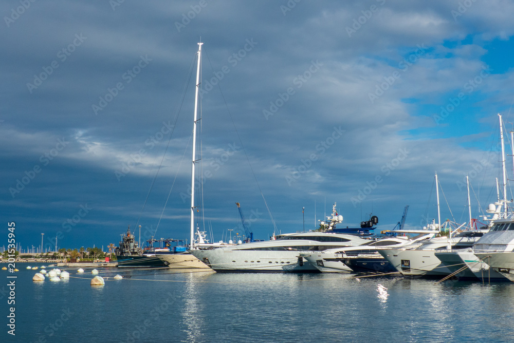 Nice view to the luxury yachts in the port of Valencia with the blue sky and clouds at sunset in spring 2018