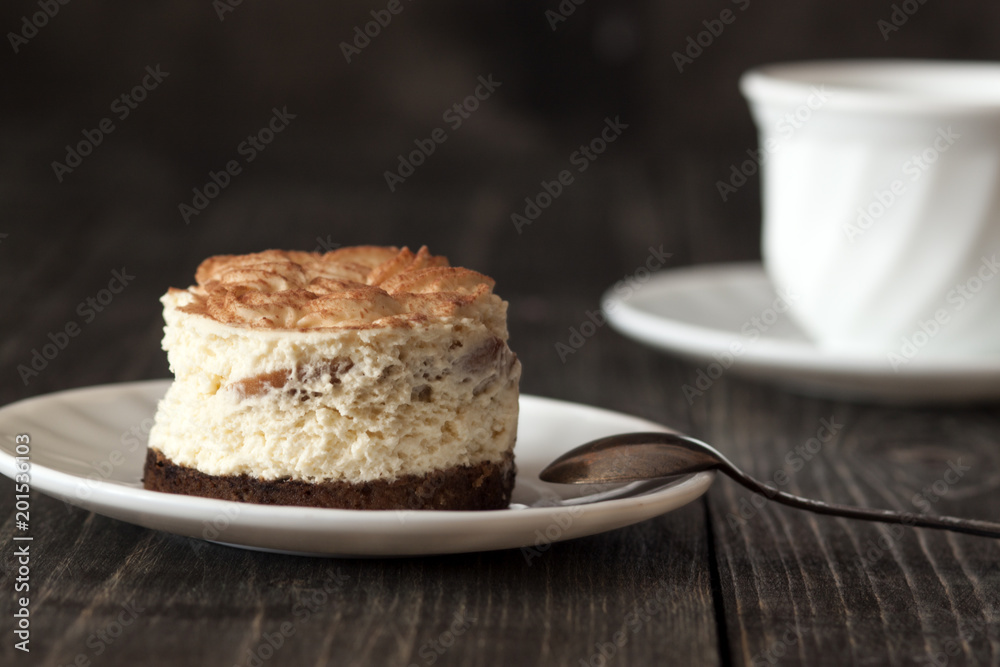 Tiramisu cake on a white saucer and a cup of black coffee Tiramisu cake on a white saucer and a cup of black coffee