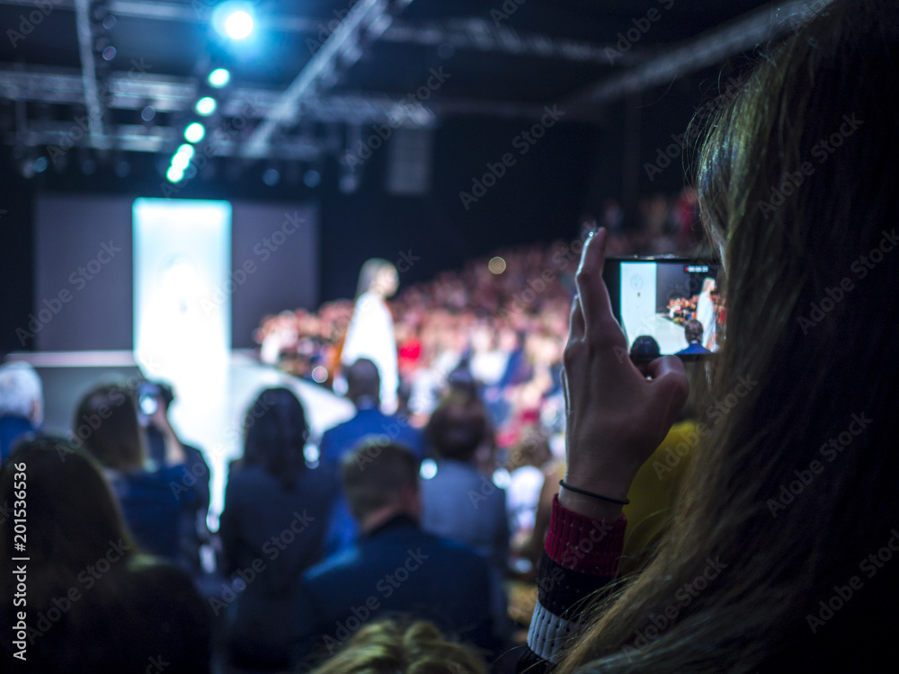 Woman holding phone during the fashion show Woman holding phone during the fashion show
