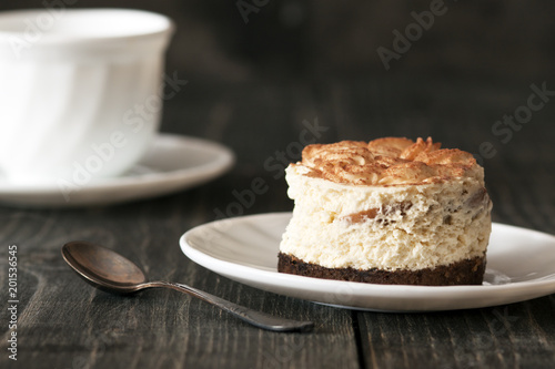 Tiramisu cake on a white saucer and a cup of black coffee