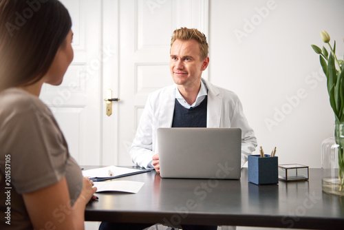 Cosmetologist consulting young woman sitting at laptop