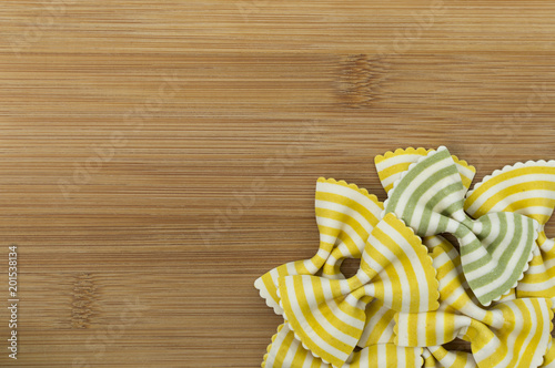 Colorful raw bow-tie  pasta on wooden background with copy space
