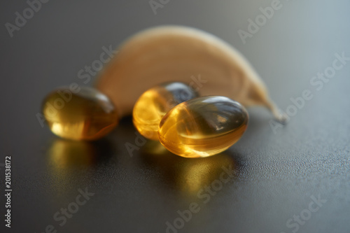 Close up golden color oil capsules and garlick clove