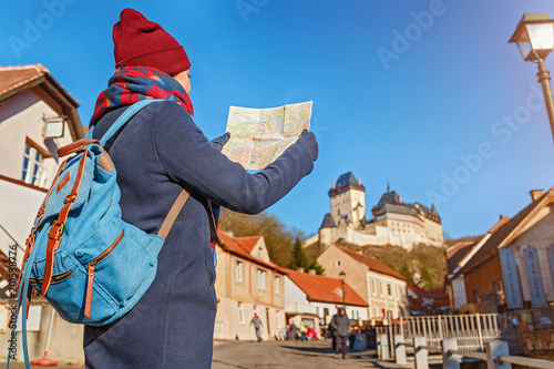  Woman traveler with backpack looking at the map near medieval gothic castle Karlstejn in Czech Reoublic at winter photo