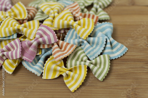 Colorful raw bow-tie  pasta on wooden background with copy space