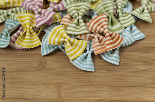 Colorful raw bow-tie  pasta on wooden background with copy space