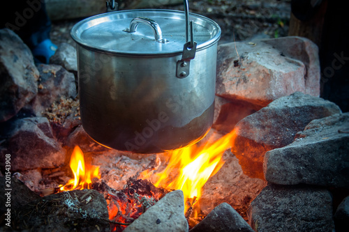 Cooking meal on burning campfire in wild camping