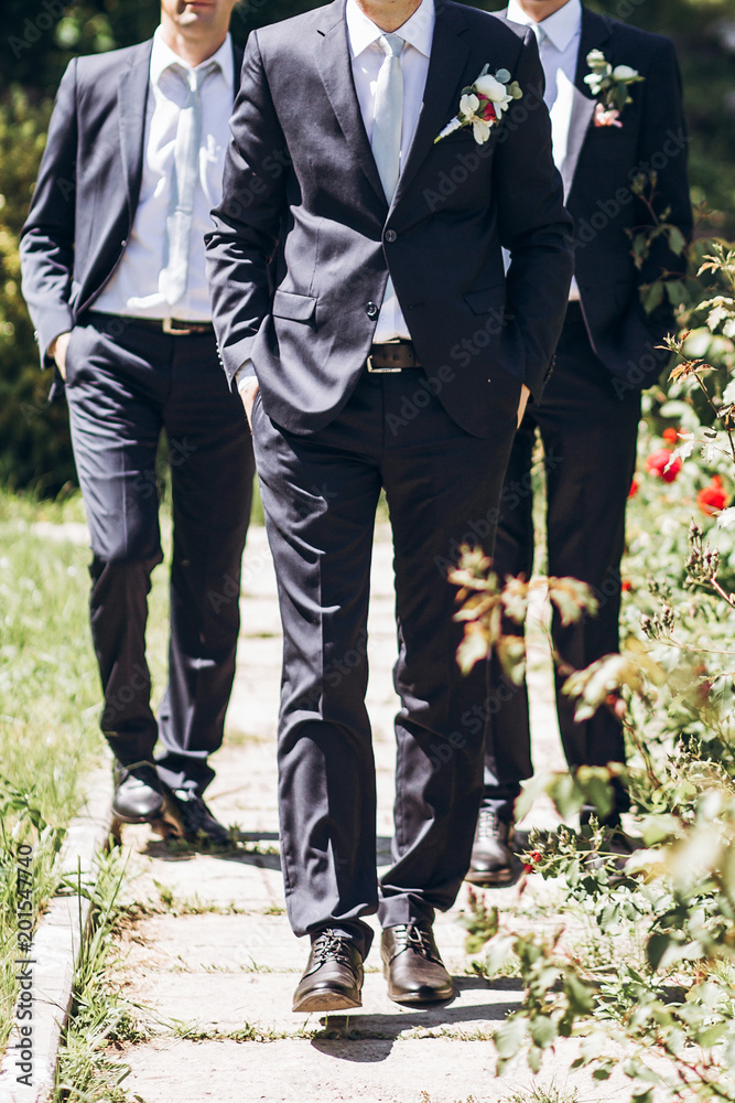 stylish groom in suit walking with groomsmen in sunny garden on wedding  day. luxury men in rich outfits standing together. friendship Stock-foto |  Adobe Stock