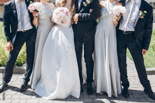 Quadro su tela gorgeous bride with peony bouquet and stylish groom posing in sunny garden with bridesmaids and groomsmen on wedding day