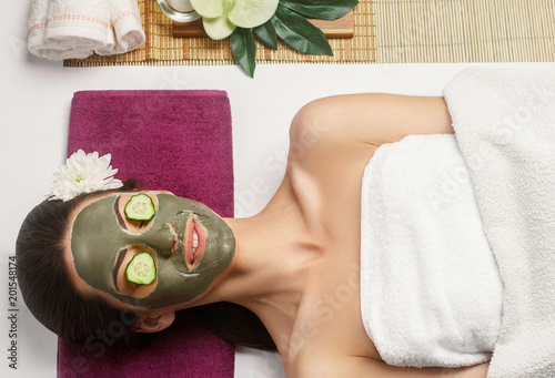 Cosmetologist smears cosmetic mask on the face of the woman in the spa salon. Spa clay mask on femele face.Skincare. Facial treatment. Cosmetology. Body care girl's photo