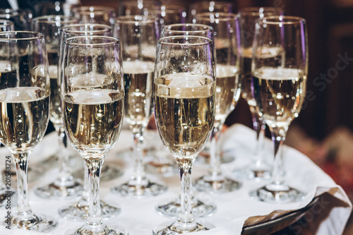 stylish golden champagne in glasses. elegant glasses of alcohol drink on tray serving at luxury wedding reception. christmas celebration. luxury catering at feast