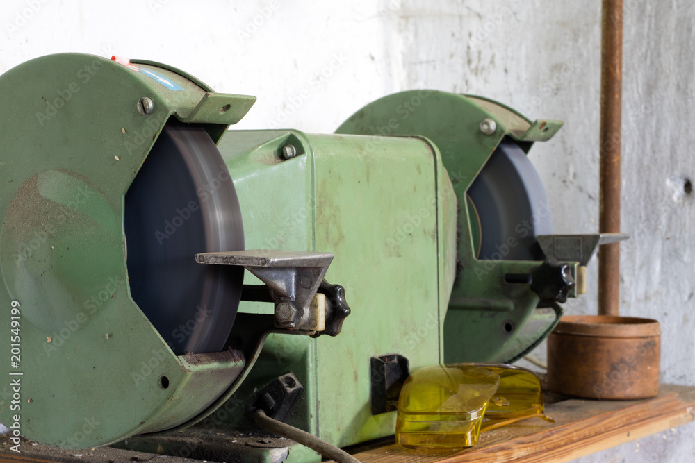 Bench grinder for locksmith's work on a wooden table. Locksmith accessories for small repairs. Bench grinder for locksmith's work on a wooden table. Locksmith accessories for small repairs.