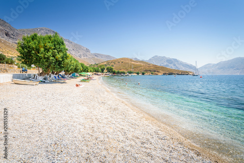 Beautiful sunny holiday coast view to the greek blue sea with crystal clear water beach relaxing with some boats fishing cruising surrounded by hills mountains  Patmos  Kos Island  Dodecanese  Greece