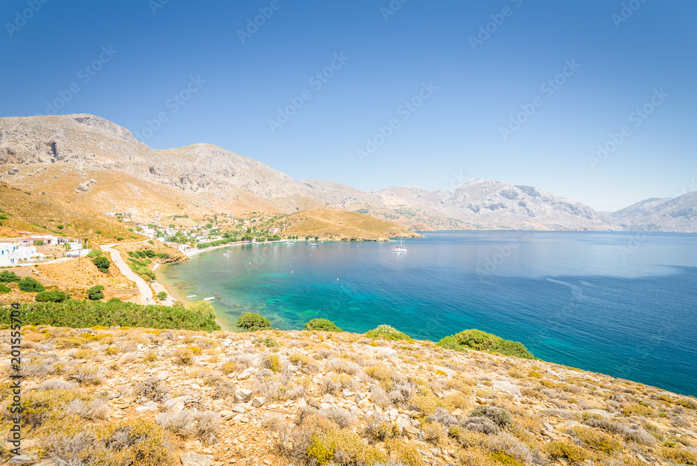 Beautiful sunny holiday coast view to the greek blue sea with crystal clear water beach relaxing with some boats fishing cruising surrounded by hills mountains, Patmos, Kos Island, Dodecanese, Greece