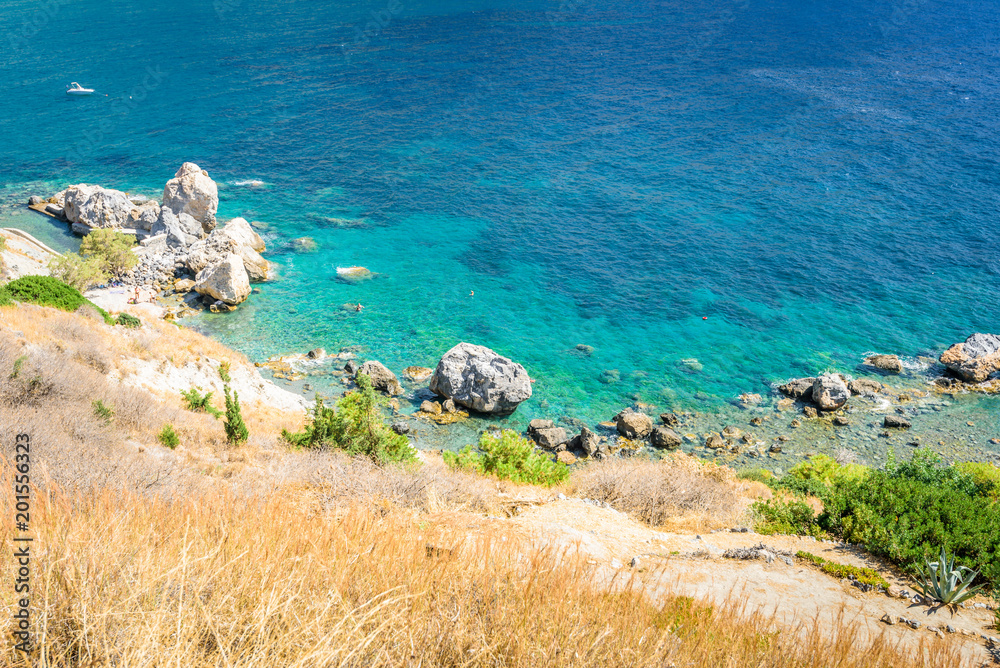Beautiful sunny coast view to the greek blue sea with crystal clear water beach with some boats fishing cruising surrounded by hills mountains, Kantouni, Patmos, Kos, Dodecanese Islands, Greece Beautiful sunny coast view to the greek blue sea with crystal clear water beach with some boats fishing cruising surrounded by hills mountains, Kantouni, Patmos, Kos, Dodecanese Islands, Greece