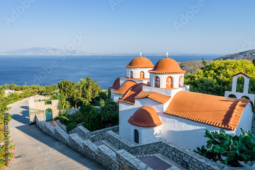 Beautiful mediterranean greek colorful holy monastery Agios Savvas situated on a mountain high above the town of Pothia, Kalymnos Island, Kos, Dodecanese, Greece photo