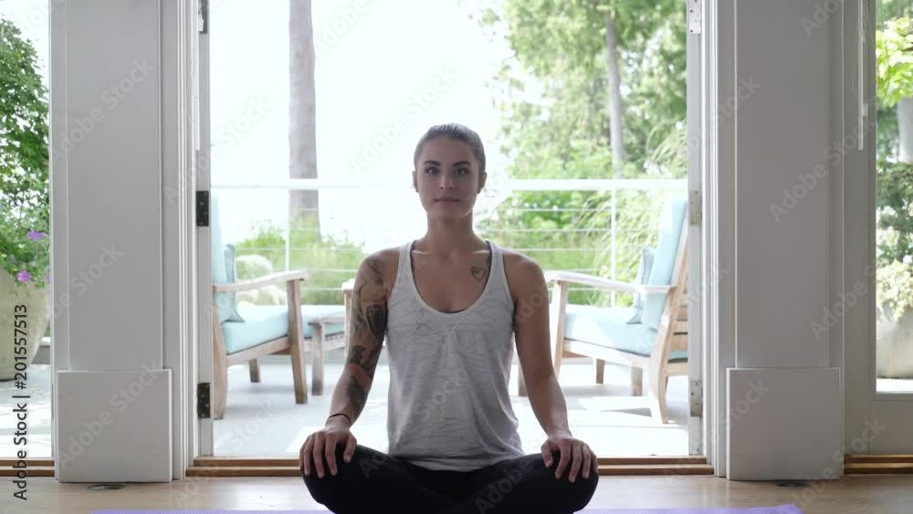 Young woman meditating on floor looking at camera.