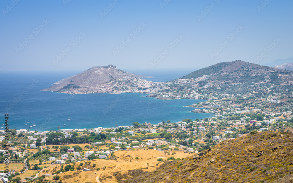 Leros Island, Dodecanese, Greece: Beautiful sunny coast view to the greek blue sea with crystal clear water beach with some boats fishing cruising surrounded by hills mountains Alinda city