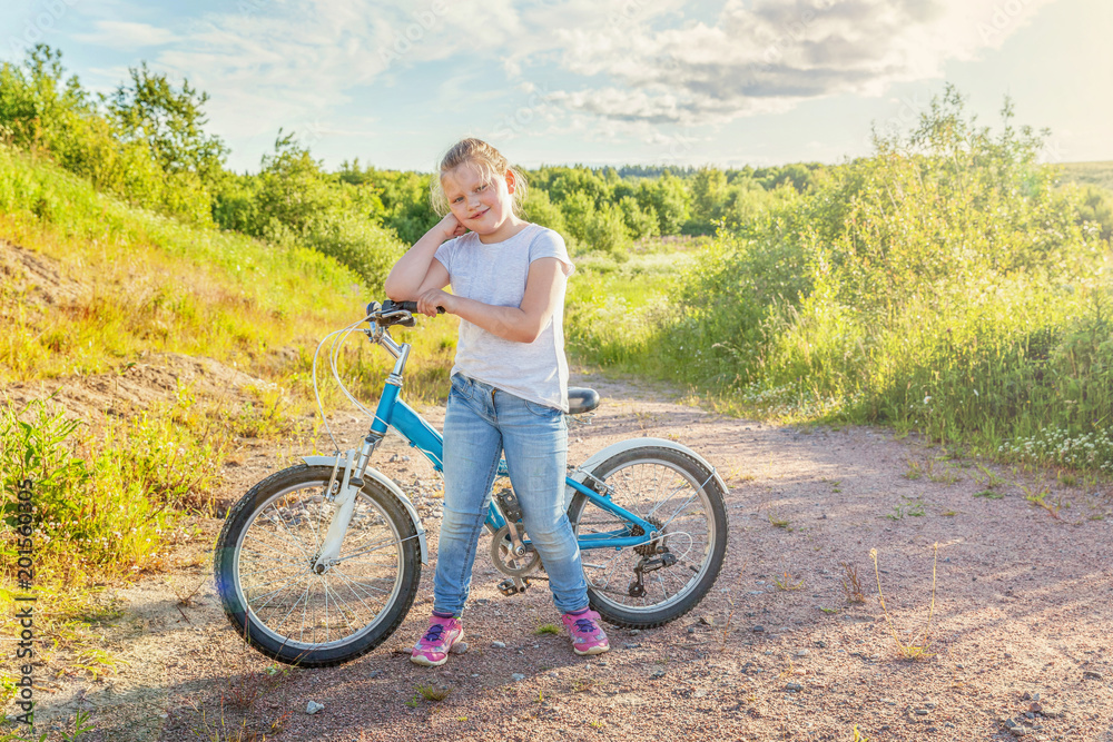 Obraz premium Happy child riding bike. Young girl on bicycle in sunny summer park. Healthy school children summer activity. Kids playing and cycling outdoors. Little girl learns to keep balance while riding bicycle