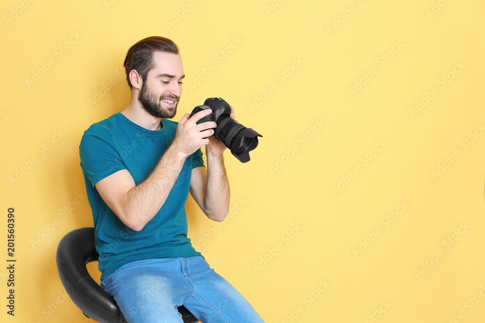 Young photographer with professional camera on color background Young photographer with professional camera on color background