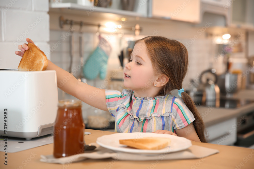 Little girl preparing toast for breakfast in kitchen