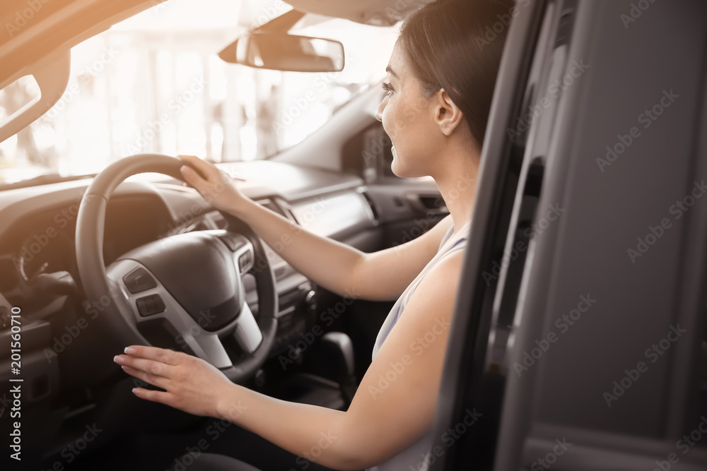 Young woman sitting in driver's seat of new car at salon Young woman sitting in driver's seat of new car at salon