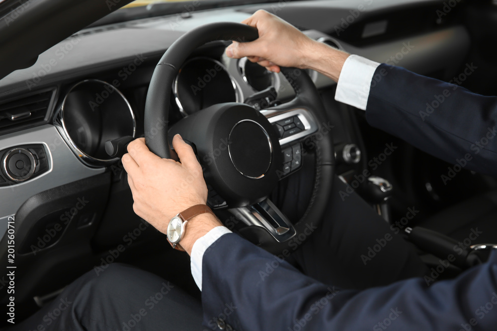 Young businessman sitting in driver's seat of auto. Buying new car