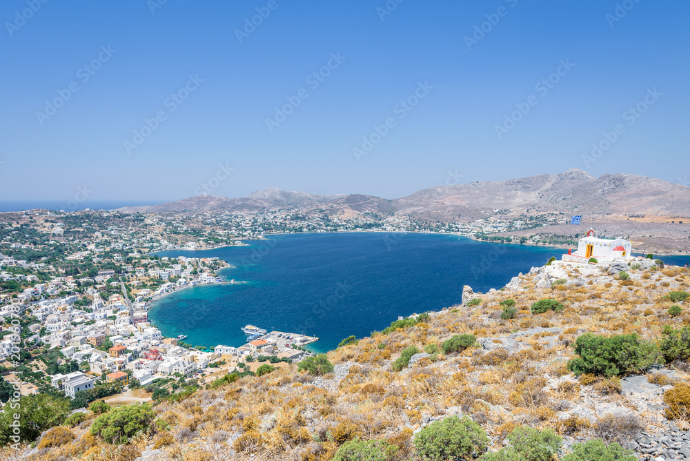 Beautiful sunny greek white church and village town Agia Marina harbor view to the greek blue sea water from the old castle surrounded mountains, Medieval Castle, Leros, Dodecanese Islands, Greece 