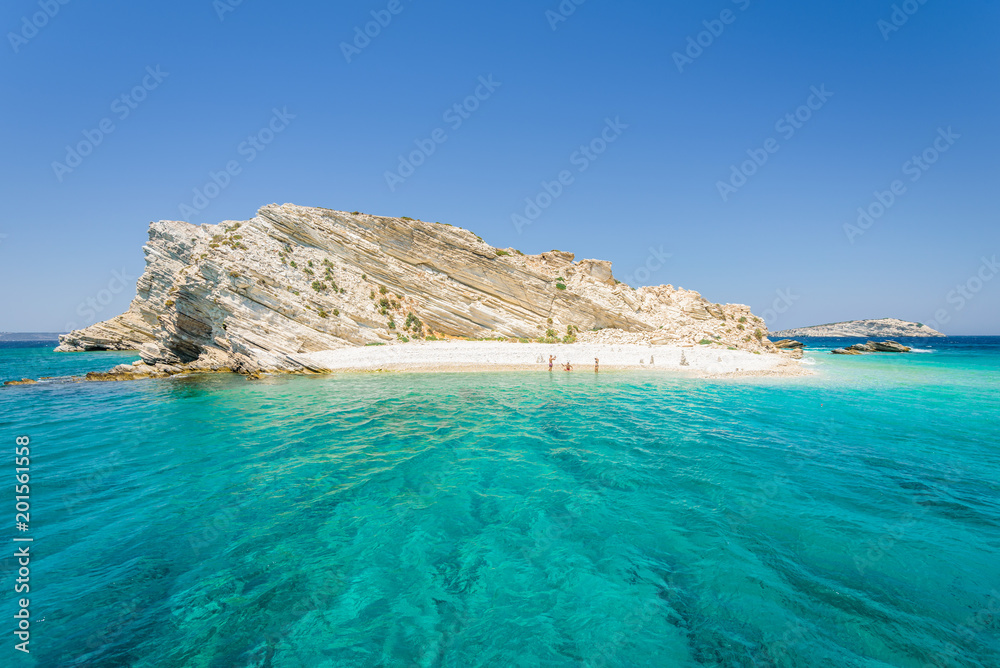 Beautiful sunny coast view to a small greek island and crystal clear blue water beach with some boats cruising and people swimming, White Island, Aspronisi, Leros, Dodecanese/ Greece – July 22 2017