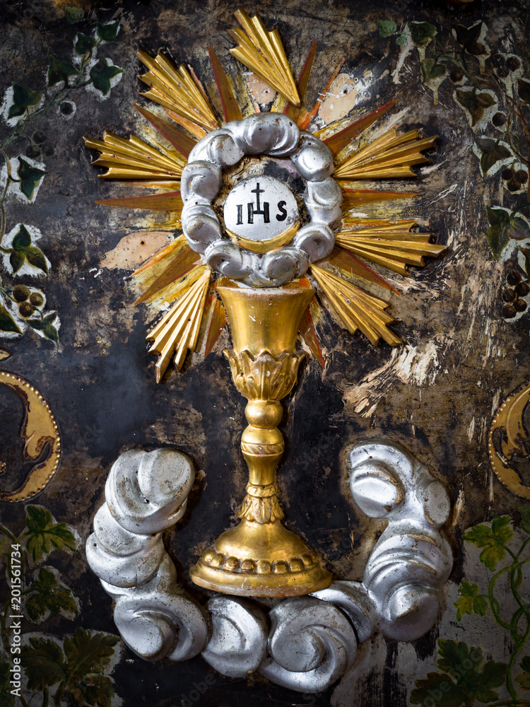 Detail of an abbey altar painted in gold with depicted the Eucharist chalice.