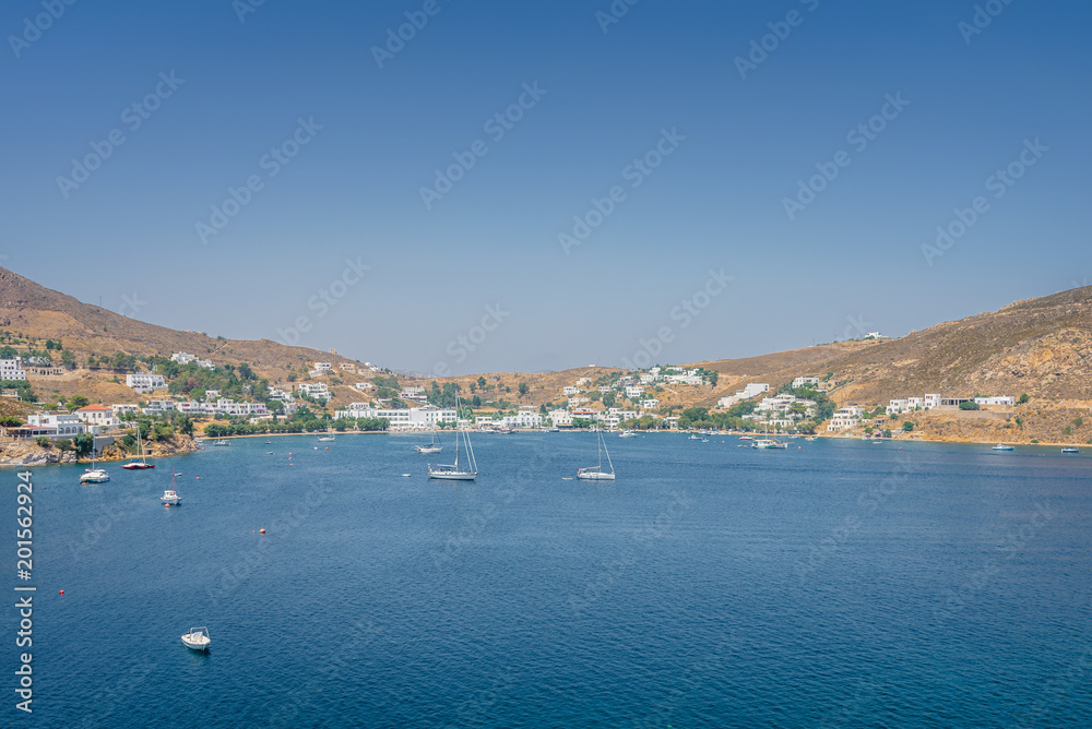 Beautiful sunny holiday coast view to a empty holiday bay with crystal clear blue water sandy greek beach for sunbathing and some boats cruising fishing, Patmos Island, Kos, Dodecanese/ Greece