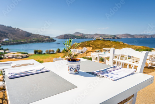 Your table is already reserved at the greek mediterranean sea behind crystal clear blue water and a beautiful coastal aegean bay with fishermen boats cruising, Patmos Island, Kos, Dodecanese, Greece