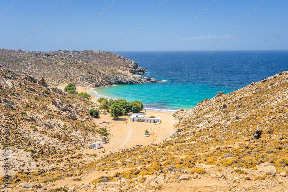 Beautiful sunny coast view to the greek beach Psili Ammos and blue aegean sea with crystal clear water sandy beach with some boats fishing cruising small hills covering, Patmos, Dodecanese, Greece 
