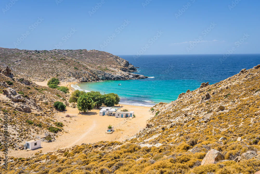 Beautiful sunny coast view to the greek beach Psili Ammos and blue aegean sea with crystal clear water sandy beach with some boats fishing cruising small hills covering, Patmos, Dodecanese, Greece