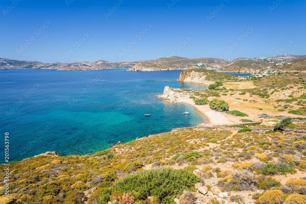 Amazing sunny coast view to a empty holiday bay Didymes beach with crystal clear blue water sandy beach for sunbathing and some boats cruising fishing in background, Patmos Island, Dodecanese, Greece