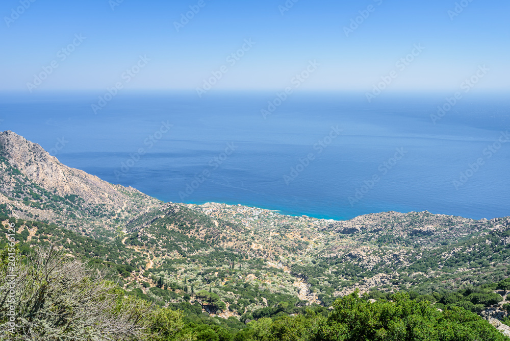 Beautiful sunny greek village town church and harbor view to the blue sea with crystal clear water and fishing boats cruising yacht at shore, Ikaria Island, Karkinagri, Sporades/ Greece – 08 01 2017