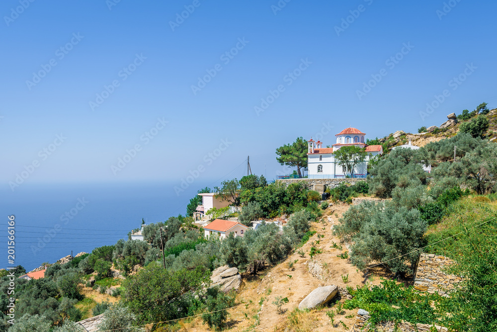 Beautiful blue white greek church basilica chapel in the middle of a small greek mountain village with views to mediterranean sea on the island of Ikaria, Vrakades Village, Sporades, Greece