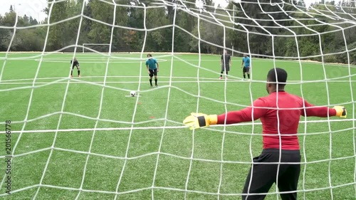 Male soccer player scoring goal.
