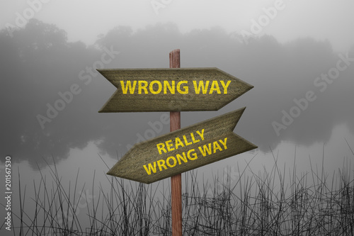 Wooden arrow signs in nature with wrong way warning