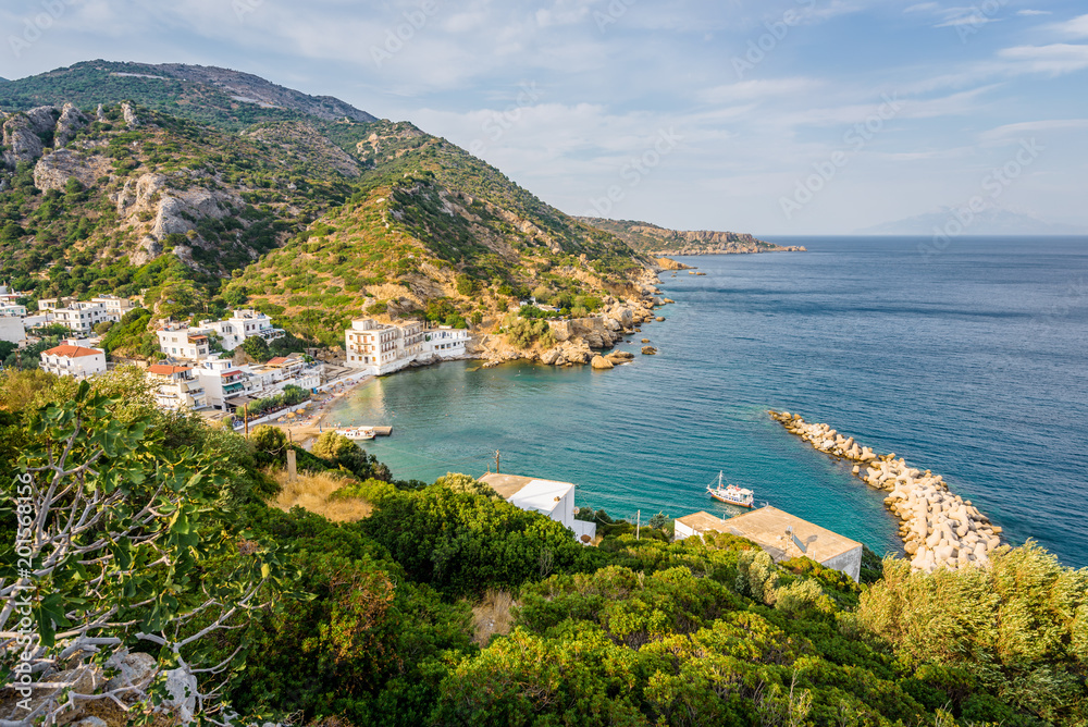 Beautiful sunny summer coast view to the greek blue sea with crystal clear water relaxing holiday beach perfect for sunbath at the shore with a small rock, Agios Kirykos, Ikaria, Sporades, Greece 