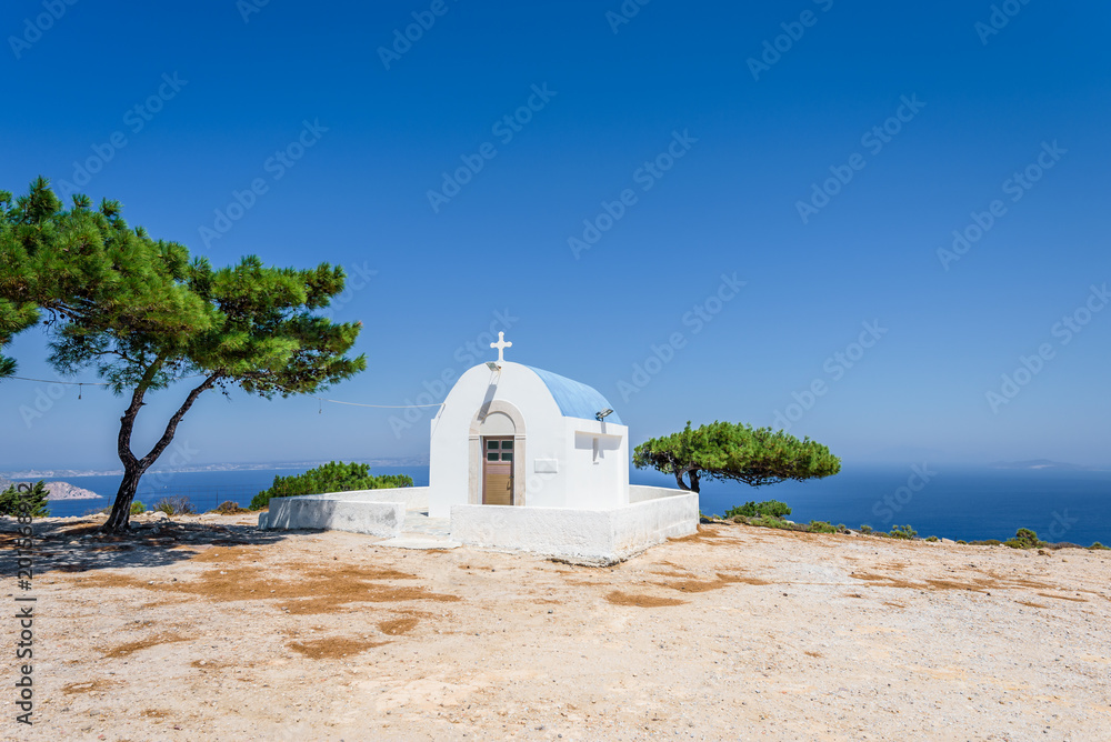 Holy white and blue greek orthodox chruch chapel of agios mamas the holy mother shining at an empty place over the greek sea hidden by the mountains on the island of Kos, Dodecanese, Greece
