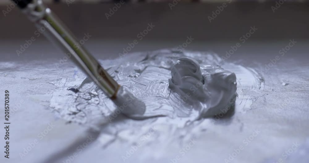 ECU detail artist dips fine sable brush into a a blob of mixed pale gray oil paint ready for painting. Hand-held 4K recorded in slow motion at 60fps.