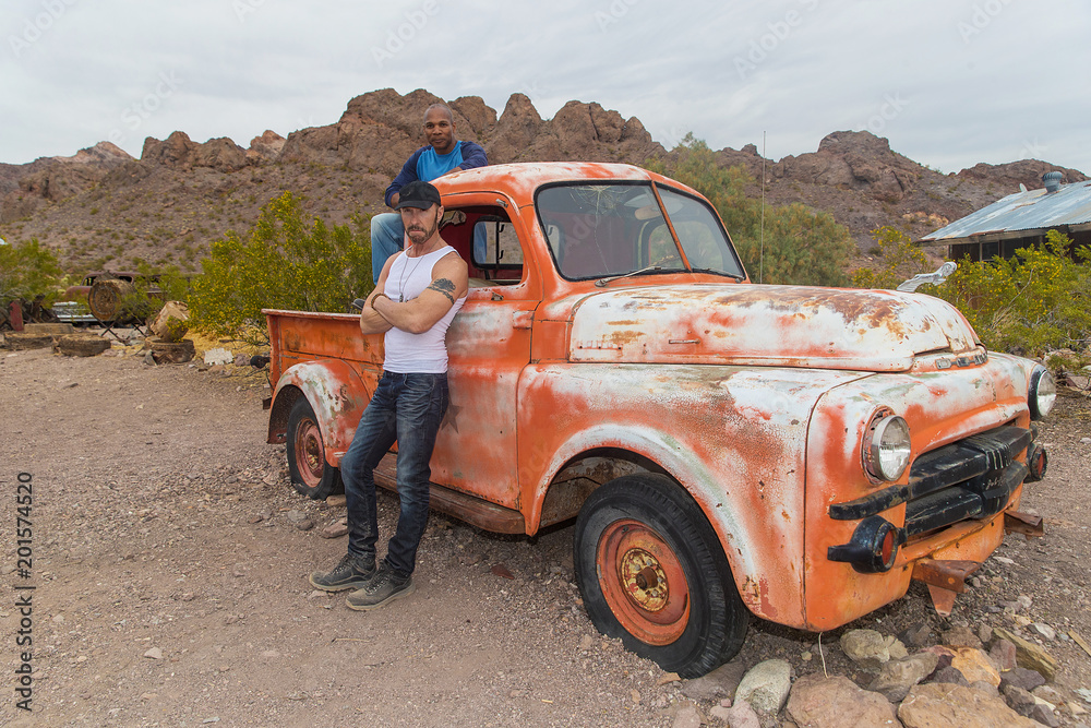 Two men and an old rusted pickup truck