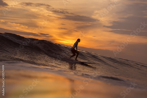 Surfer girl in ocean at sunset time