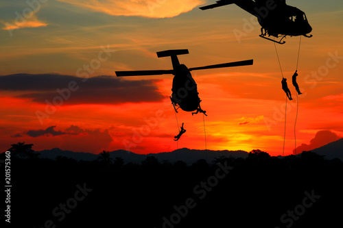 Silhouette Soldiers rappel down to attack from helicopter with sunset and copy space add text   Concept stop hostilities To peace 